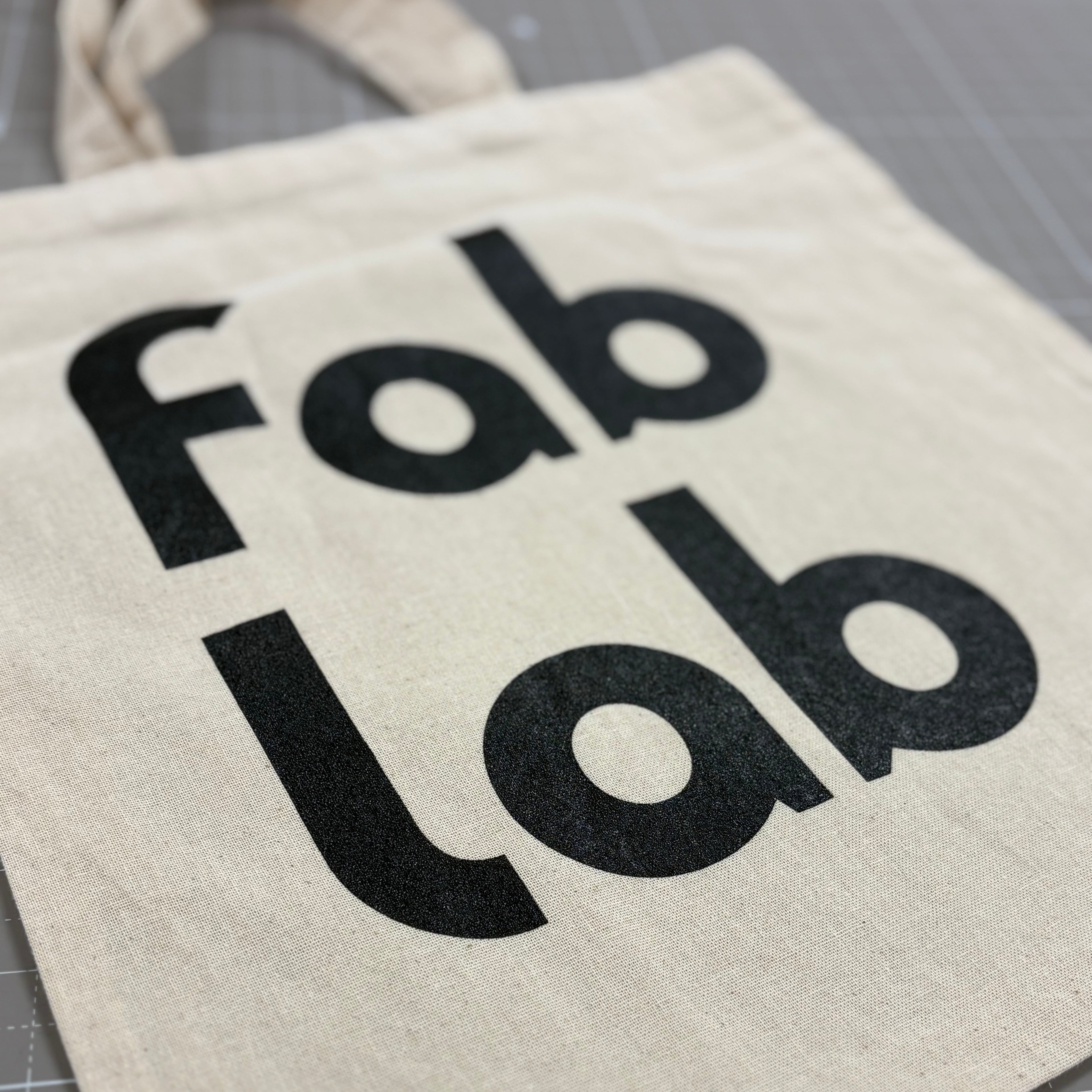Canvas tote bag with 'Fab Lab' text on a gray surface